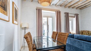 Una stanza con un tavolo da pranzo in vetro, sedie in vimini, un divano blu e una lampada intrecciata.