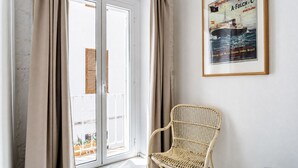 Una stanza con una sedia in vimini, una porta scorrevole in vetro e un quadro appeso al muro.