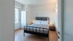 Une chambre à coucher avec un lit, des lampes de chevet, une porte et une fenêtre.