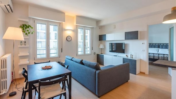 A modern apartment with a dining area, sofa, kitchenette, and a bed in the background. - Nolo Flat - Metro Turro & Wi-Fi (Milan)