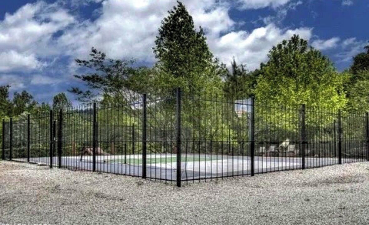 A fenced outdoor area with trees and a gravel ground.