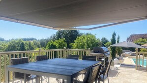 A covered patio with a table and chairs, a grill, and a pool. - Villa sleeps 10 with heated pool & jacuzzi and breathtaking views (Coux and Bigaroque-Mouzens)