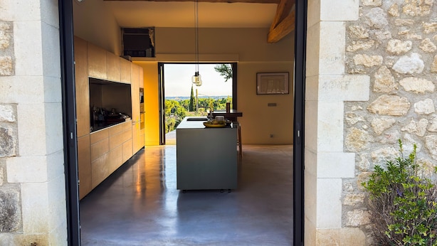 Une cuisine moderne avec vue, des murs en pierre et un banc en bois.