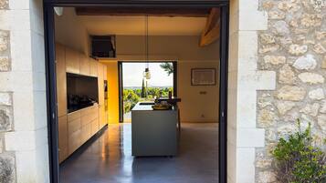 Une cuisine moderne avec vue, des murs en pierre et un banc en bois.