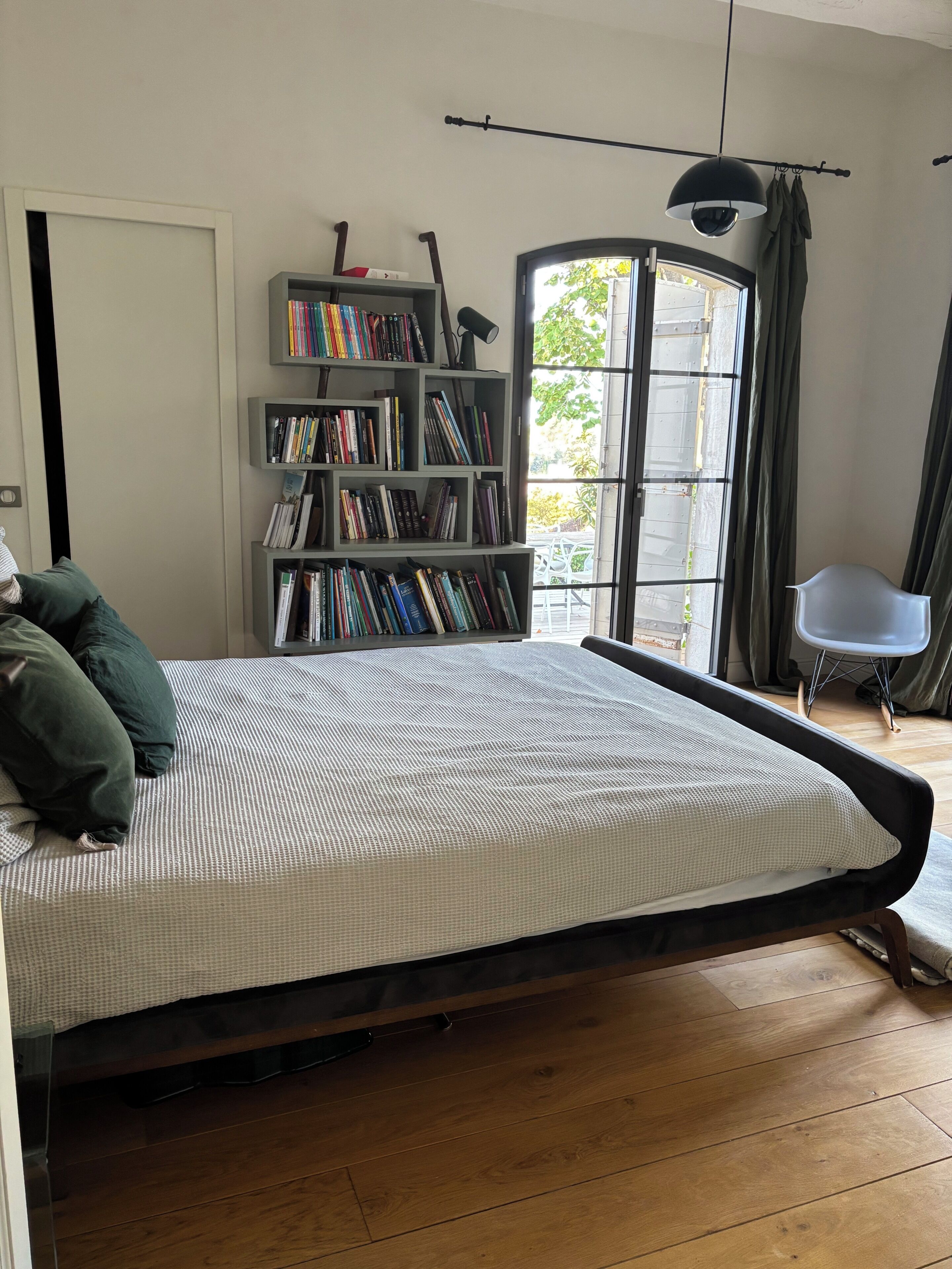 Une chambre à coucher avec un lit, une bibliothèque, une fenêtre et une chaise.