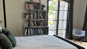 Une chambre à coucher avec un lit, une bibliothèque, une fenêtre et une chaise.