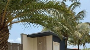 A modern building with a small entrance, a door, and a pathway leading to it. - 3-Suite Condo Steps to Palm Beach (Noord)