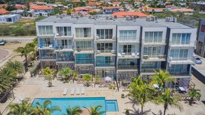 A multi-story hotel with a rooftop pool, balconies, and a view of the surrounding neighborhood. - 3-Suite Condo Steps to Palm Beach (Noord)