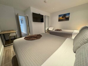 Une chambre d’hôtel avec deux lits, un bureau, une chaise, une télévision et un tableau au mur.