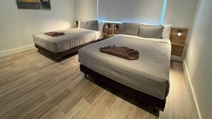 A bedroom with two beds, a nightstand, a wall-mounted light, and a painting. - 3-Suite Condo Steps to Palm Beach (Noord)