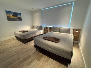 Ein Schlafzimmer mit zwei Betten, einem Nachttisch, einer Wandleuchte und einem Bild.