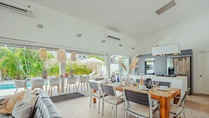 Una cocina moderna con horno empotrado, refrigerador y comedor con mesa y sillas de madera.