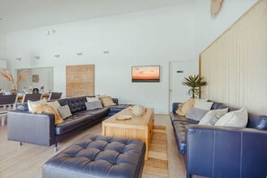 A modern living room with a sectional sofa, a coffee table, and a large painting. - Villa Lua (Noord)