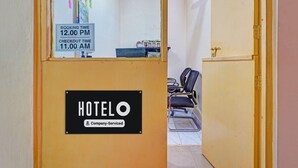 Hotellin vastaanottoalue, jossa on ilmoitustaulu varausten aikatauluineen, vastaanottotiski ja oleskelualue tuoleineen.