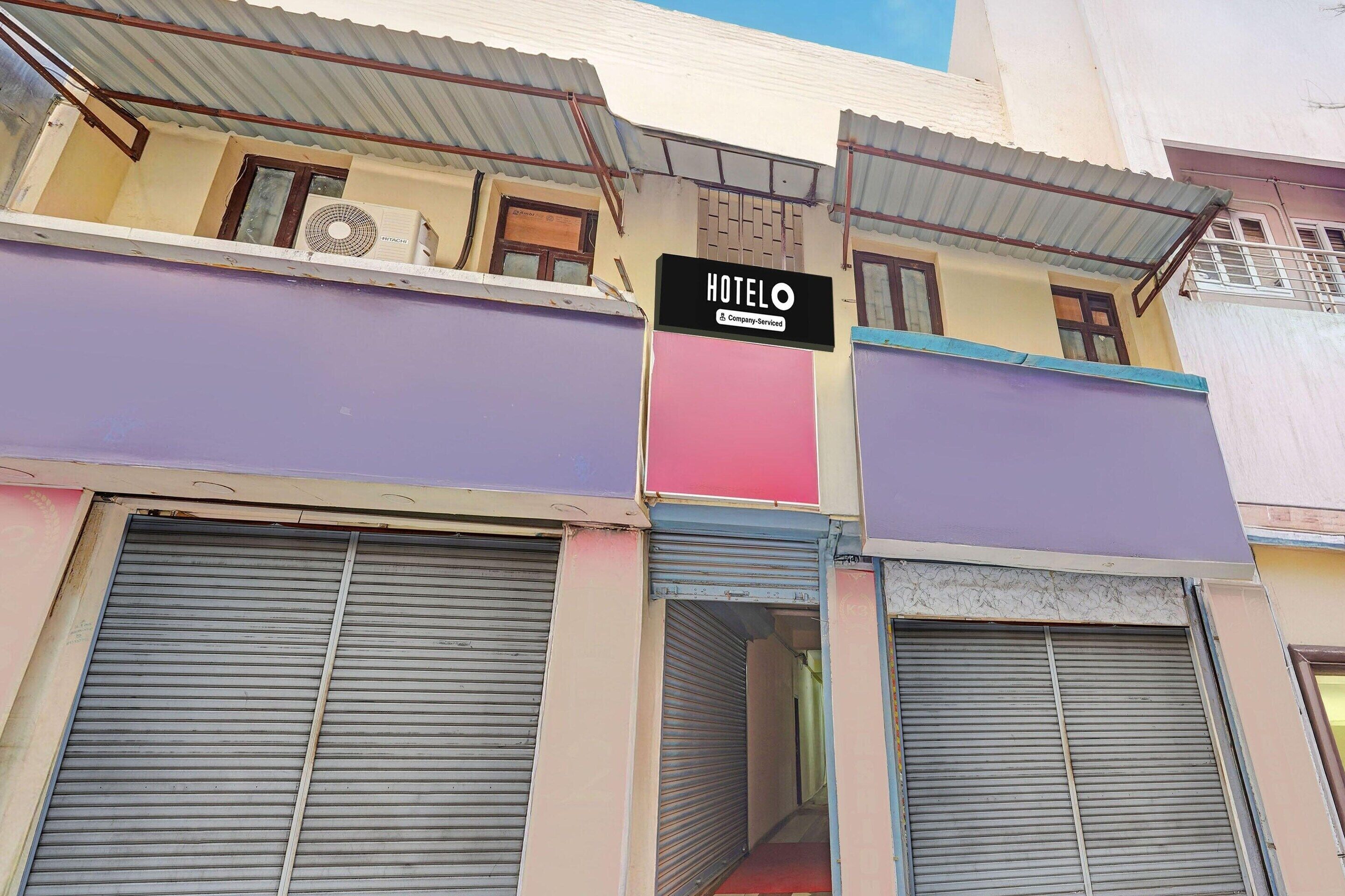 A hotel with a signboard, closed shutters, and a visible air conditioning unit.