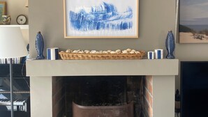 A fireplace with a framed artwork above it, a television on the right, and a wicker basket on the mantel. - On the edge of the dune! sleeps 10, pool 100 m from the beach, all on foot!!! (Moliets-et-Maa)