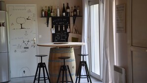A kitchen with a wooden barrel, stools, a whiteboard with drawings, and wine bottles on shelves. - On the edge of the dune! sleeps 10, pool 100 m from the beach, all on foot!!! (Moliets-et-Maa)