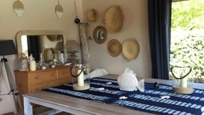 A dining area with a wooden table, benches, a blue patterned tablecloth, and a wall decorated with hats and a mirror. - On the edge of the dune! sleeps 10, pool 100 m from the beach, all on foot!!! (Moliets-et-Maa)