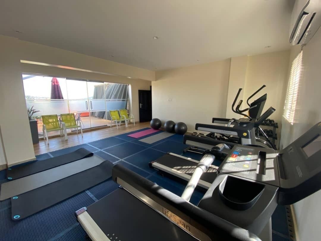Un gimnasio con cintas de correr, pelotas de ejercicio y una máquina de remo.