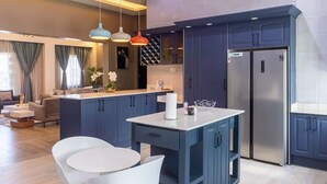 A modern kitchen with dark blue cabinets, a stainless steel refrigerator, and pendant lighting. - BELLEVIEW APARTMENTS (Kampala)