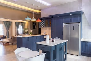A modern kitchen with dark blue cabinets, a stainless steel refrigerator, and pendant lighting. - BELLEVIEW APARTMENTS (Kampala)