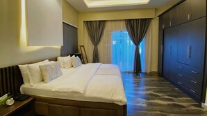 A hotel room with a large bed, a wardrobe, and a view of the outdoors. - BELLEVIEW APARTMENTS (Kampala)