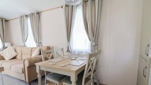 Ein gemütliches Wohnzimmer mit einer Couch, einem Esstisch, Stühlen und Vorhängen.