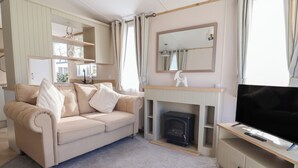 Ein Wohnzimmer mit einem beigen Sofa, einem Kamin, einem Fernseher und einem Spiegel.