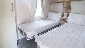 Ein Schlafzimmer mit zwei Betten, einem Holzregal darüber und einer Nachttischlampe.