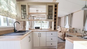 Eine kompakte Küche mit Holzauszug, einer Spüle und einem Essbereich mit Tisch und Stühlen.