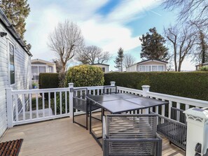 A deck with a table and chairs, surrounded by white railings and a hedge. - Elsie Rose (Ruthin)