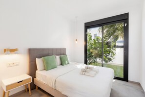 Un dormitorio moderno con cama, mesita de noche y vistas a través de una puerta de cristal.