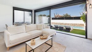 Un salon moderne avec un grand canapé, une table basse et une vue sur une piscine et un jardin.