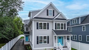 A two-story house with a front porch, a covered entryway, and a small front yard. - Luxury Modern Boston Townhome w/ Parking! (Boston)