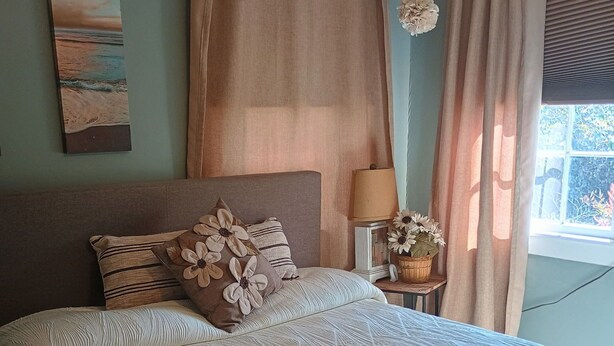 A bed with a textured white cover, a headboard, and decorative pillows. - Tranquil 1-bedroom cottage with AC in charming Augusta near the Masters! (Augusta)