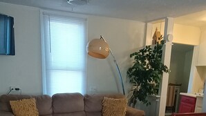 A living room with a sofa, a lamp, a plant, and a rug. - Tranquil 1-bedroom cottage with AC in charming Augusta near the Masters! (Augusta)