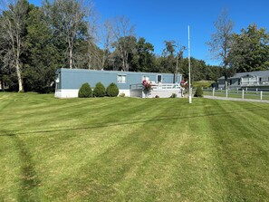 A blue mobile home with a fenced yard, surrounded by trees. - 2-bedroom mobile home in Henderson (Henderson)