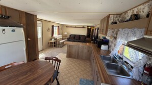 A compact kitchen with a dining table, a refrigerator, a stove, and a sink. - 2-bedroom mobile home in Henderson (Henderson)