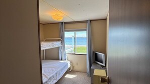 A hotel room with a bunk bed, a desk with a television, and a window with a view of the sea. - 2-bedroom mobile home in Henderson (Henderson)