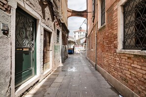 A narrow alleyway with brick buildings, a green door, and a white awning. - ROMANTIC ATTIC WITH A VIEW OF THE GRAND CANAL (VENEZIA)