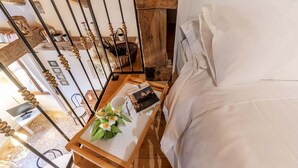 Un dormitorio con estructura de cama de madera, una mesita de noche con un libro y una taza, y vista al interior de la habitación.