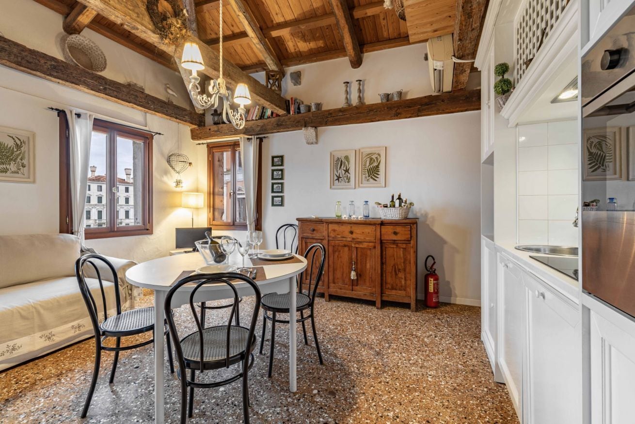 A cozy dining area with a round table, chairs, and a wooden ceiling.