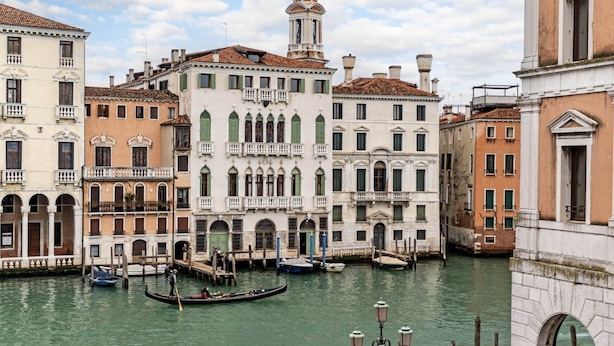 Un canal con góndolas, edificios históricos y una torre destacada.
