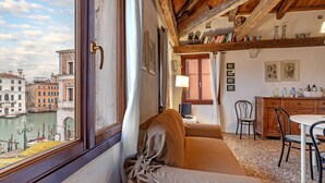 Una habitación con vista a un canal, un sofá, una mesa de comedor y un techo de madera.