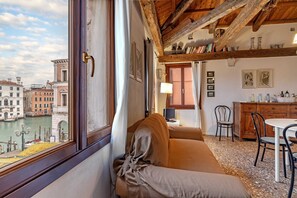 A room with a view of a canal, a sofa, a dining table, and a wooden ceiling. - ROMANTIC ATTIC WITH A VIEW OF THE GRAND CANAL (VENEZIA)