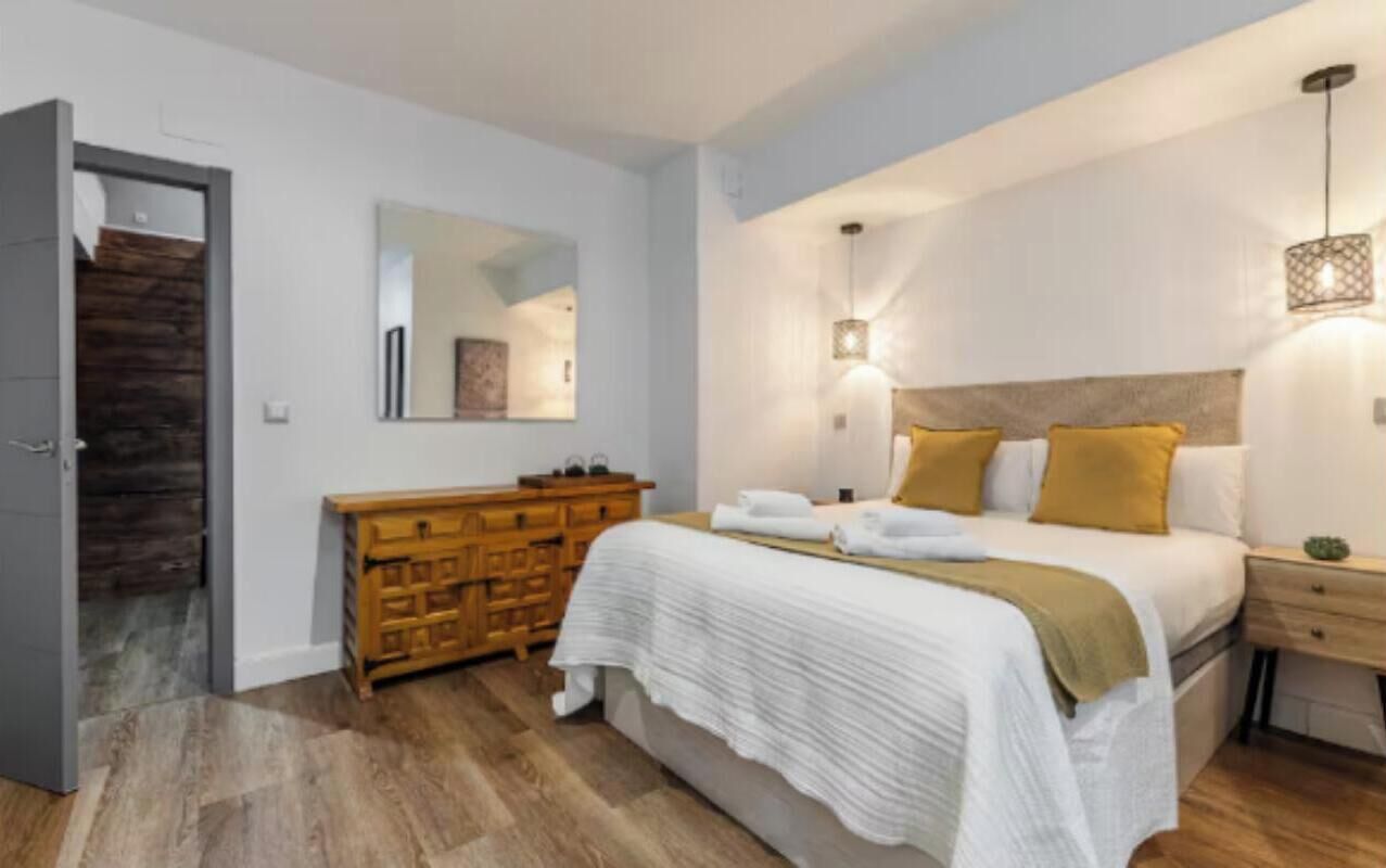 Une chambre à coucher comprenant un lit, une table de chevet, une commode et un miroir.