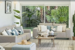 A living room with two sofas, a coffee table, and a large window with a view of greenery.