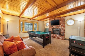 A cozy room with a pool table, a fireplace, and a television.