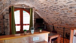 Tunnelmallinen huone, jossa on kivinen katto, puinen tiski, televisio ja pieni kaktus.