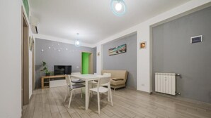 Una sala de estar moderna con una mesa de comedor, sillas, un sofá, un televisor y un radiador.